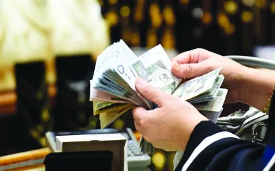 A Saudi woman counts banknotes at a jewellery shop in the Tiba gold market in the capital Riyadh (file). Unusually for a period of high oil prices, Saudi banks are facing a shortage of liquidity. A rapid rise in lending that’s not been matched by deposit growth has left banks clamouring for funding.