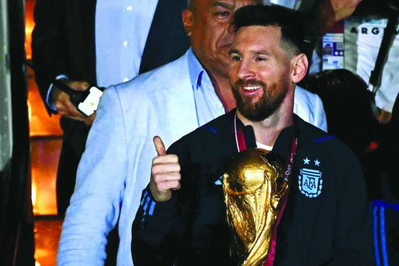 Argentina’s captain and forward Lionel Messi holds the FIFA World Cup Trophy upon arrival at Ezeiza International Airport in Buenos Aires yesterday early morning. (AFP)