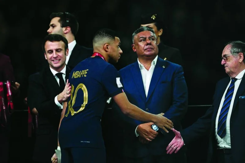France’s forward Kylian Mbappe is consoled by French President Emmanuel Macron (left) as he shakes hands with the president of the French Football Federation, Noel Le Graet (right) next to the President of the Argentine Football Association Claudio Tapia during the trophy ceremony in Lusail on Sunday. (AFP) 