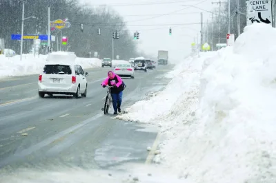 Wendy Aeh makes her way along Lake Shore Road avoiding large piles of snow in Derby, New York.