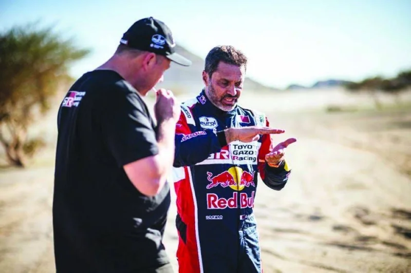 Toyota’s driver Nasser al-Attiyah of Qatar talks to a crew member after a practice session by the Red Sea in Yanbu, Saudi Arabia, yesterday, ahead of the 2023 Dakar Rally. 