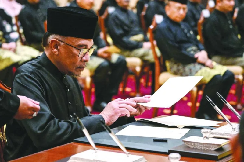 Malaysia’s newly appointed Prime Minister Anwar Ibrahim signs documents after taking the oath during the swearing-in ceremony at the National Palace in Kuala Lumpur on November 24, 2022. (Reuters)