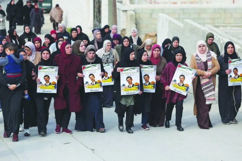 Palestinian women march during the funeral procession of Ahmad Kahla carrying posters depicting him, in the village of Rammun in the occupied West Bank, yesterday.