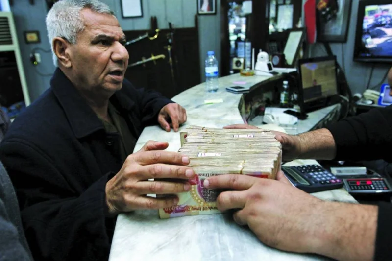 A man changes Iraqi dinars to US dollars at a currency exchange shop in Baghdad (file). Iraq's local currency has been on a two-month roller coaster ride following a tightening of procedures for international transfers, with some blaming Washington for the dinar's woes.