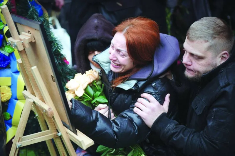 Relatives grieve as they look at the photo of Mykhaylo Korenovsky, a Ukrainian boxing coach, who died following a missile strike last week on a residential building, during his funeral in Dnipro, eastern Ukraine, yesterday. (AFP)