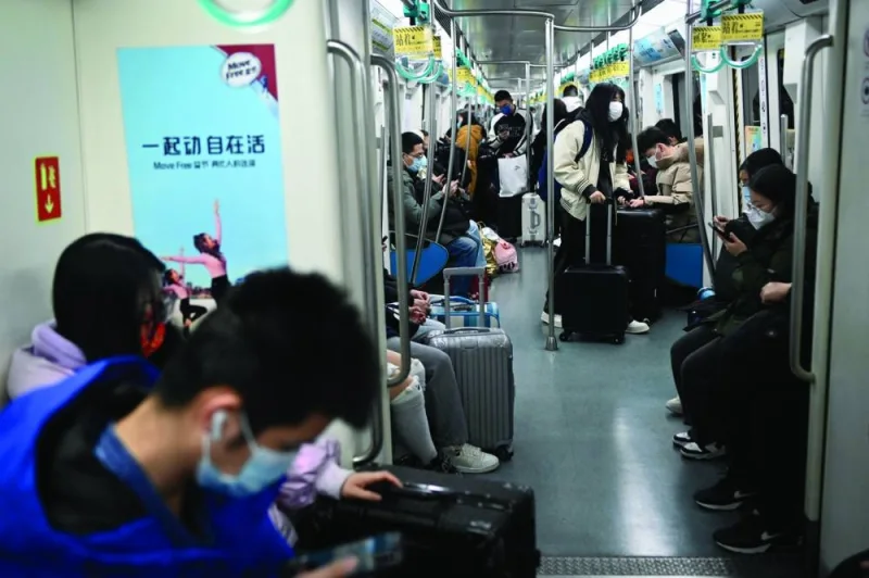 Passengers take a subway train with their luggages in Beijing on Thursday.