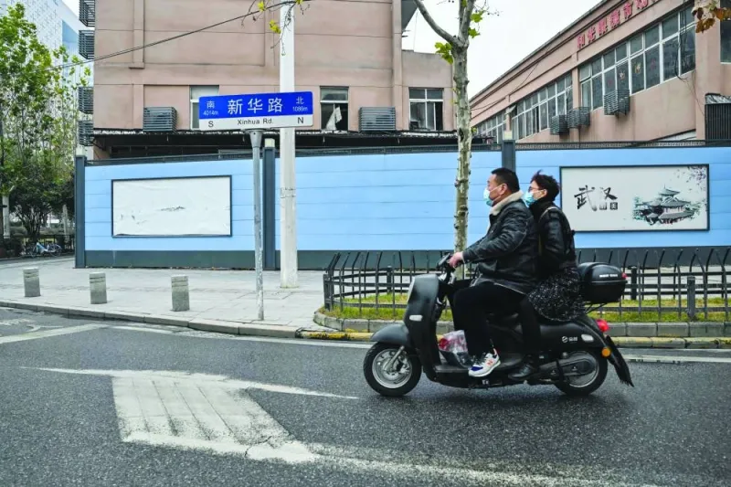 People ride a scooter next to the closed Huanan Seafood Wholesale Market, where the Covid-19 coronavirus was first detected, in Wuhan in China’s central Hubei province, yesterday.