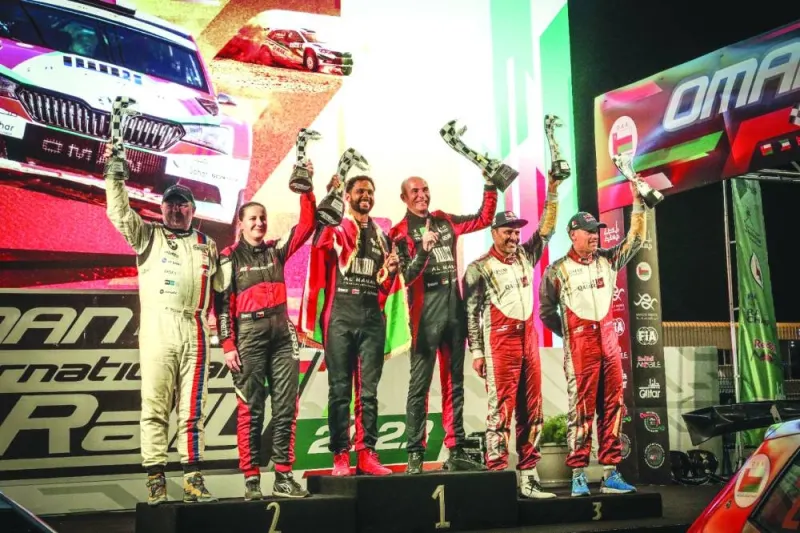 Oman Rally winners celebrate with their trophies on the podium.