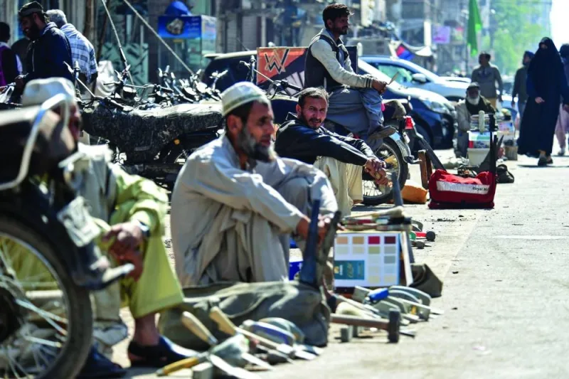 Daily wage labourers sitting along a road as they wait to be hired for day jobs in Pakistan's port city of Karachi. Pakistan is gripped by a major economic crisis, with the rupee plummeting, inflation soaring and energy in short supply.
