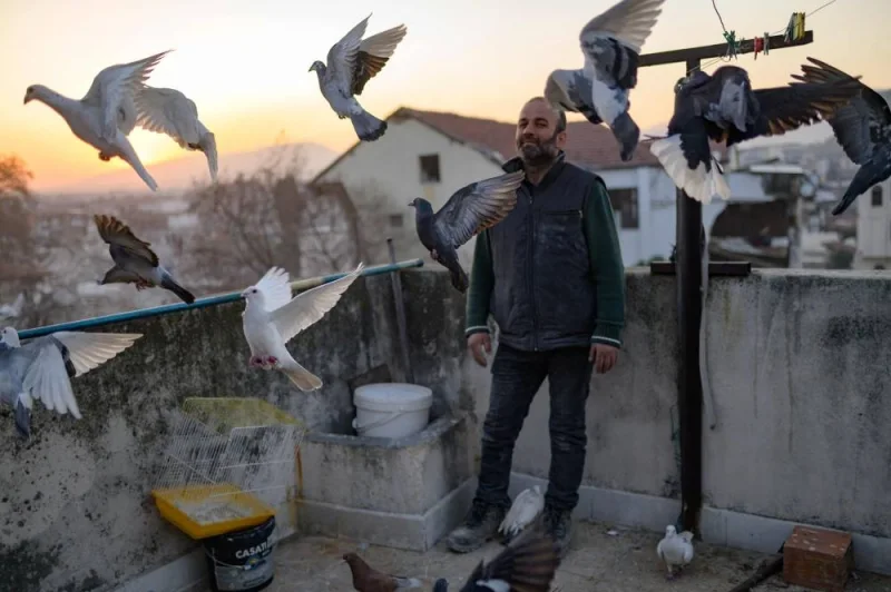 Murat Guzel scatters bird food on the roof of a restaurant where he worked before the earthquake, in Antakya south of Hatay (AFP)