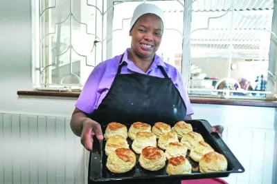 Veronica Makonese, a cook at Bottom Drawer, an upscale tearoom in Harare, uses a scone cutter to shape scone dough made from simple ingredients of flour, salt, yeast, sugar and milk, in Harare. Right: Makonese displays freshly baked scones.