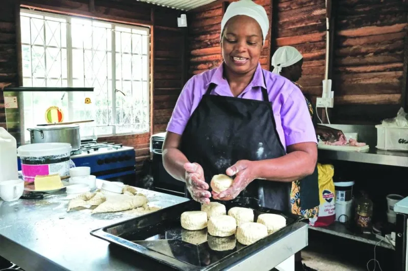 Veronica Makonese, a cook at Bottom Drawer, an upscale tearoom in Harare, uses a scone cutter to shape scone dough made from simple ingredients of flour, salt, yeast, sugar and milk, in Harare. Right:  Makonese displays freshly baked scones.