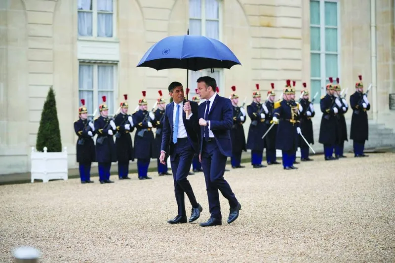 French President Emmanuel Macron, uses an umbrella to protect Britain's Prime Minister Rishi Sunak after a French-British summit at the Elysee Palace in Paris, France, yesterday.