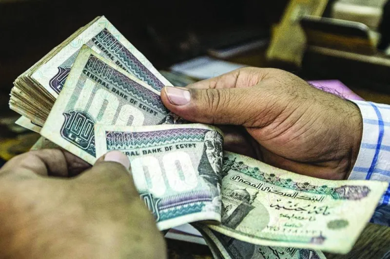 A man counts Egyptian pound banknotes at a currency exchange shop in downtown Cairo (file). Traders are on a record-long streak of hedging against a decline in the Egyptian pound as some Wall Street banks warn growing pressures on the currency could soon force the central bank’s hand in allowing another devaluation.