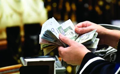 A Saudi woman counts banknotes as she makes a purchase at a jewellery shop in the Tiba gold market in the capital Riyadh (file). The world’s largest oil exporter has largely moved in lockstep with the US to protect its currency peg to the dollar even as the Fed embarked on its most aggressive tightening campaign in a generation to cool off inflation.