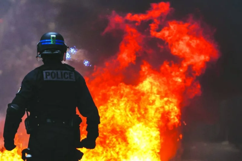 A French police officer in riot gear stands next to a fire during a demonstration in Bordeaux, southwestern France.