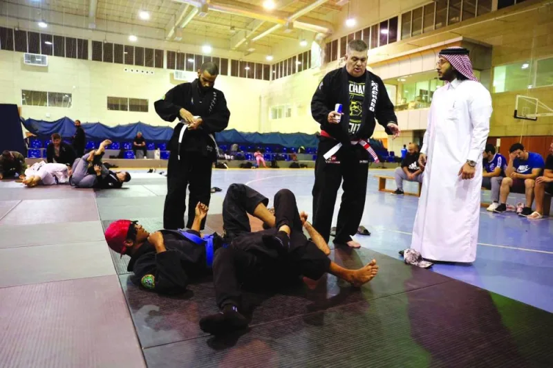 Qatar Wrestling Federation (QWF) president Sheikh Fahad bin Khalid al-Thani and Rigan Machado discuss the finer points of jiu-jitsu during a training session among athletes.