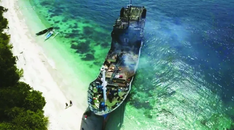 People walk towards the burnt passenger ferry Lady Mary Joy 3 after it was towed to the shores of Hadji Muhmatad, Basilan province, southern Philippines.