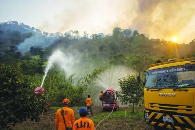 A disaster response team sprays water as they attend to a forest fire on a mountain-side in Nakhon Nayok province, northeast of Bangkok yesterday.