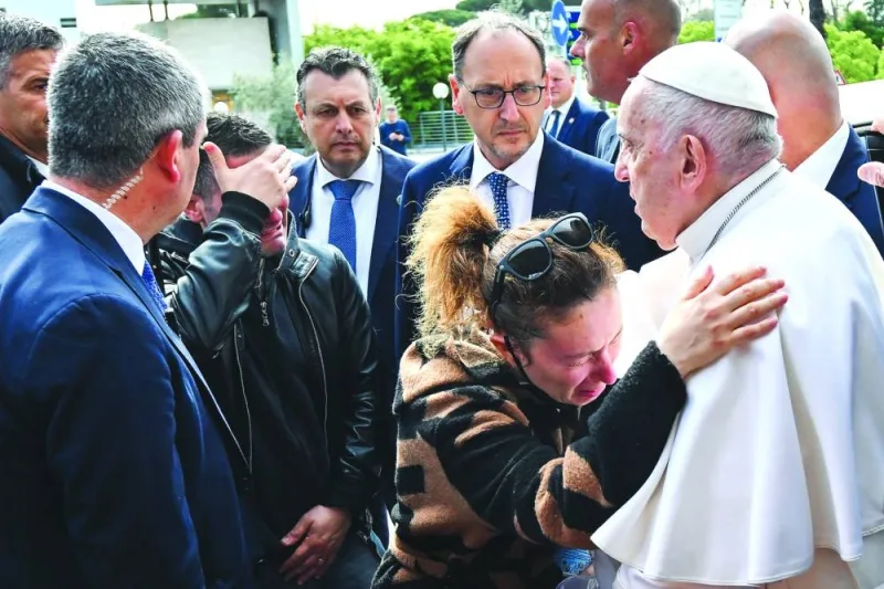 Pope Francis hugs Serena Subania as her husband Matteo Rugghia (left) reacts, a couple who lost their five-year-old child a day earlier, as the Pope leaves the Gemelli hospital yesterday in Rome after being discharged following treatment for bronchitis. (AFP)