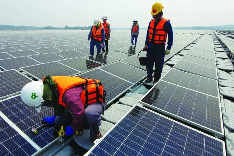 (File photo) A worker kneels by one of the solar cell panels over the water surface. (Reuters)