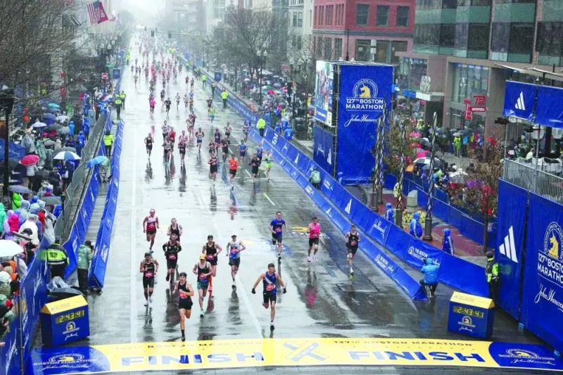 Runners celebrate in the rain as they cross the finish line during the 127th Boston Marathon in Boston, Massachusetts. (AFP)