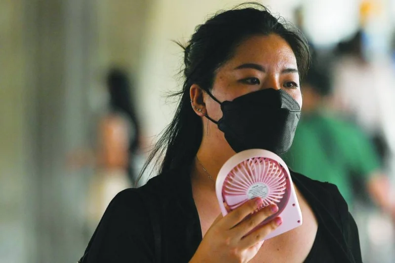 A woman uses a hand fan in Bangkok.