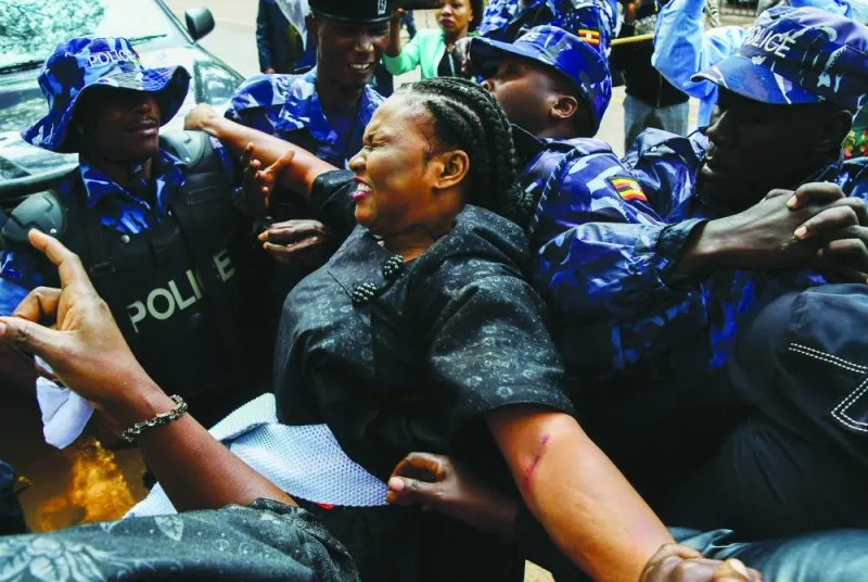 Riot police officers attempt to detain Soroti City Woman Member of Parliament Joan Acom Alobo, as female opposition legislators participate in a protest at the ministry of internal affairs in Kampala to deliver a petition over the brutality against them.