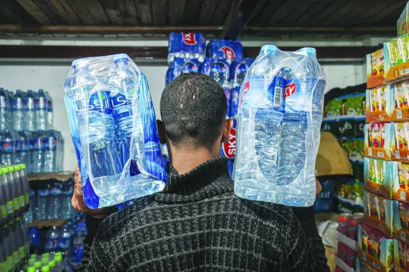 A picture taken on Saturday shows a Palestinian vendor carrying packs of bottled water at a store in Gaza City.