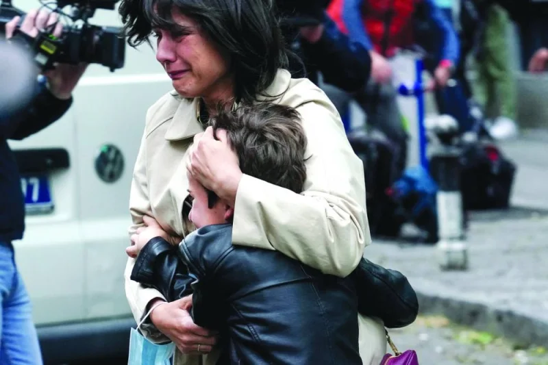 A parent escorts her child following the shooting in Belgrade on Wednesday. (AFP)