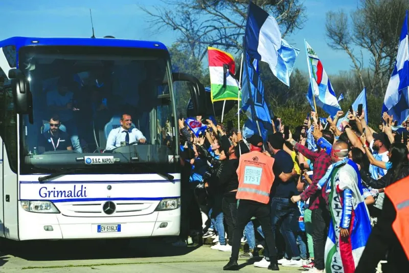 A bus transporting Napoli players drives past fans gathering outside the club’s training centre in Castel Volturno, north of Naples, to welcome victorious players a day after Napoli won Serie A title. (AFP)