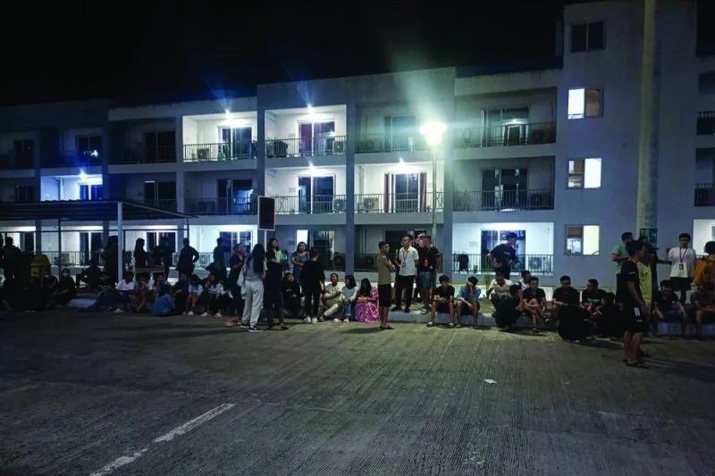 This handout photo received from the Philippine National Police anti-cybercrime group yesterday shows rescued trafficked people from Asian countries standing outside a building after a police raid inside a freeport zone in Mabalacat City, in Pampanga province, north of Manila.