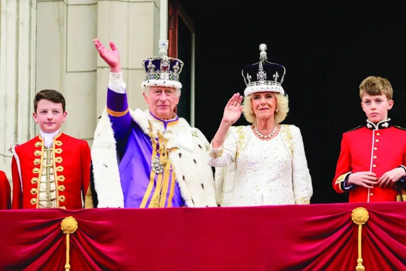 King Charles III and Britain&#039;s Queen Camilla wave to the crowds from the Buckingham Palace balcony as they wait for the Royal Air Force fly-past in central London.