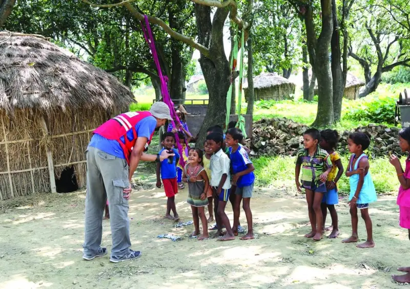 A humanitarian worker engages with young children.