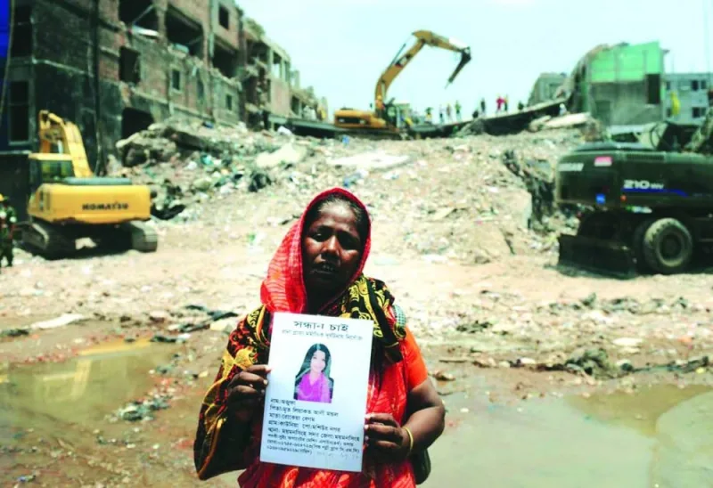 
A family member poses as she holds up the portrait of her missing relative, believed to be trapped in the rubble of an eight-storey building collapse in Savar, on the outskirts of Dhaka, on May 3, 2013 in this file photo. (AFP) 