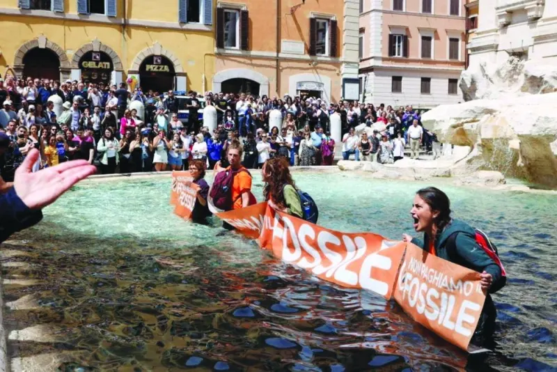 Climate activists hold a banner after pouring vegetable charcoal in the Trevi Fountain water during a protest against fossil fuels in Rome on Sunday in this image obtained from social media. (Reuters)