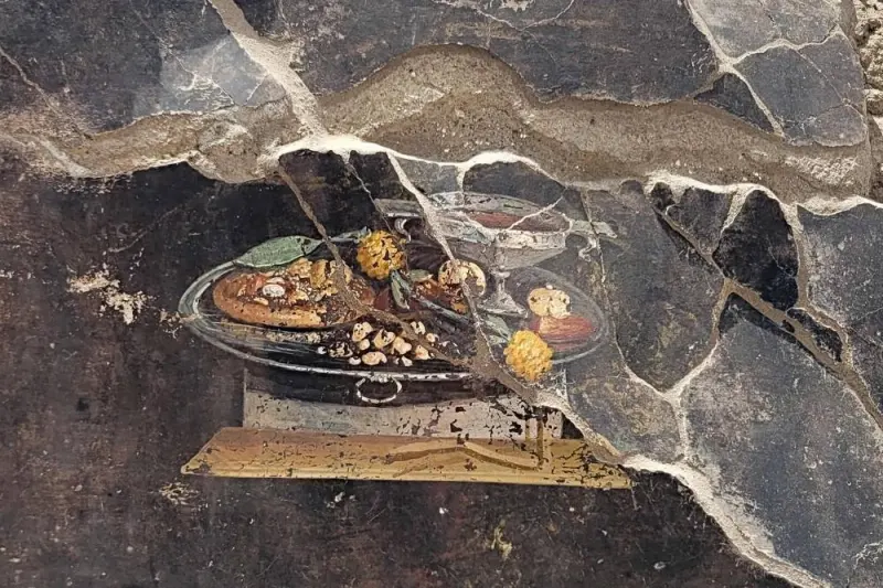 This handout photo taken and released on June 25 by Parco Archeologico di Pompei (Archaeological Park of Pompeii), shows a 2,000-year-old Pompeian painting, a still life, found by the new Regio IX excavations on the wall of an ancient Pompeian house, showing what could be a distant ancestor of modern pizza.