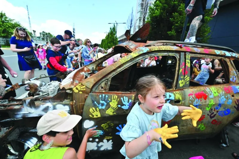 
Children decorate a burned car with colourful handprints for the local ‘Museum of Memory’ during an art event in Bucha, north of Kyiv. 