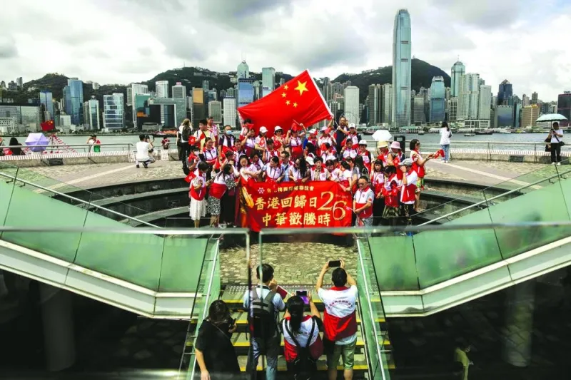 People wave the flags of Hong Kong and China on the Tsim Sha Tsui water front in Hong Kong yesterday as they celebrate the 26th anniversary of the city's handover from Britain to China.