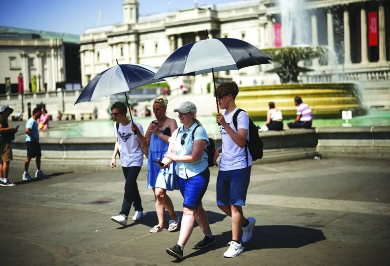 
File photo: People carry umbrellas to hide in their shadow during a heatwave, at Trafalgar Square in London, in July last year. 