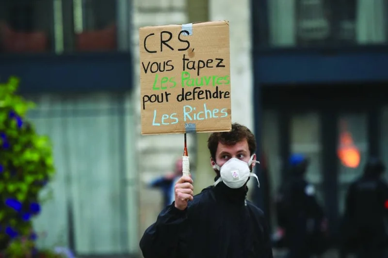 
A man holds a placard that reads ‘CRS (police) you bash the poor to defend the rich’, during a protest in Nantes. 