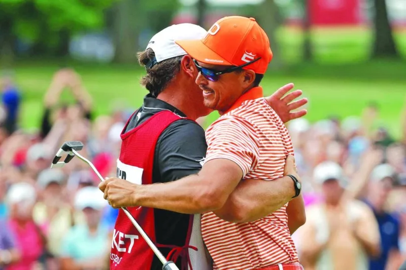 Rickie Fowler of the US celebrates with his caddie, Ricky Romano, after winning on the first playoff hole during the final round of the Rocket Mortgage Classic at Detroit Golf Club on Sunday. (AFP)