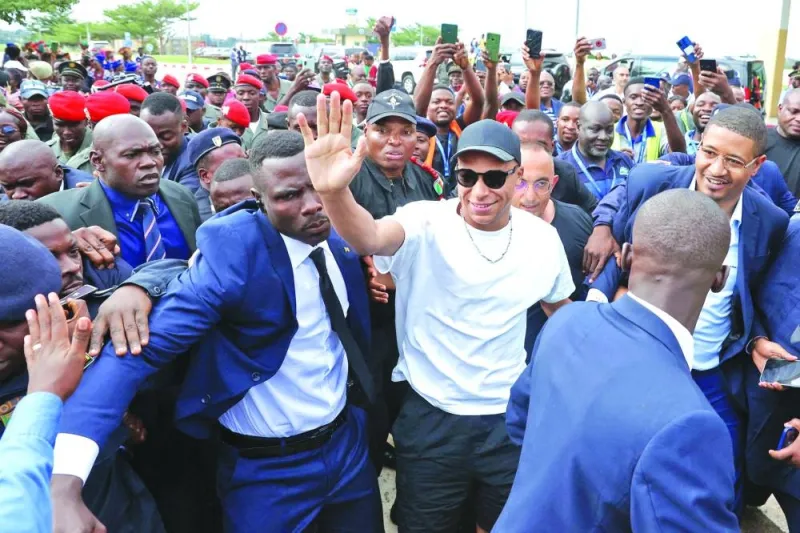 
Paris Saint-Germain and France football team star striker Kylian Mbappe (centre) greets crowds gathered outside at the Yaounde Airport in Yaounde as he arrives for a charity visit and a tour of his father’s village. (AFP) 