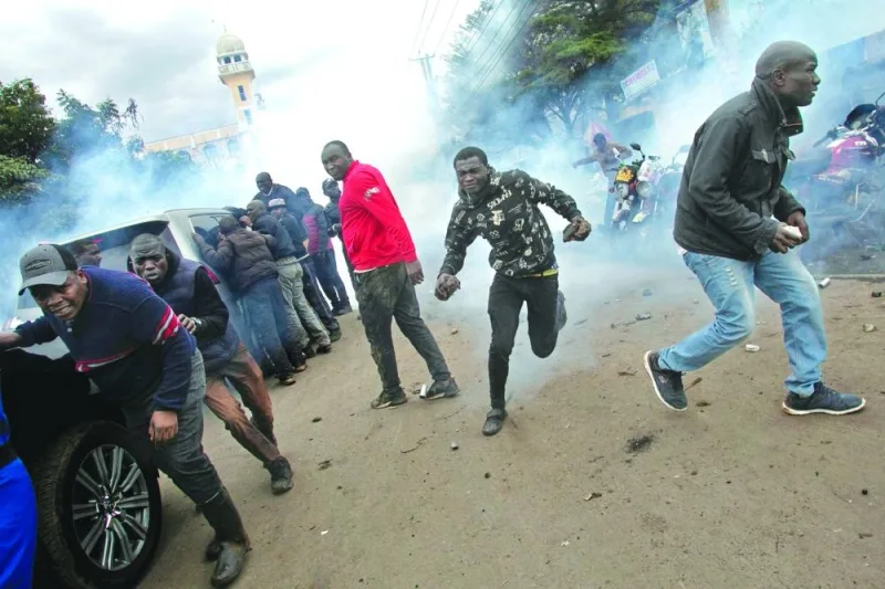
Protesters retreat from a cloud of tear gas after police fired canisters at the convoy of opposition leaders led by Raila Odinga during demonstrations against the high cost of living in Nairobi, yesterday. 