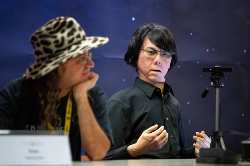 SingularityNET CEO Ben Goertzel (L) and a tele-operated android "Geminoid HI-2" attend what was presented as the World&#039;s first press conference with a panel of AI-enabled humanoid social robots in part of International Telecommunication Union (ITU) AI for Good Global Summit in Geneva. Fabrice COFFRINI / AFP