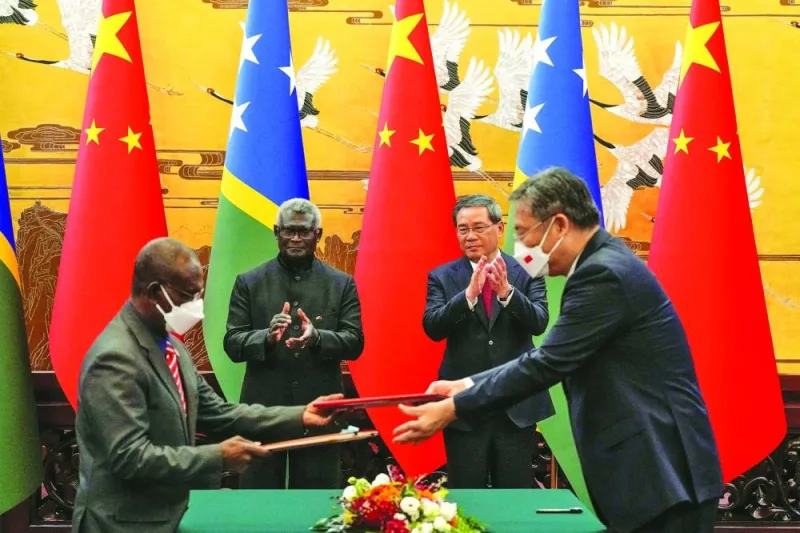 
Solomon Islands Prime Minister Manasseh Sogavare and Chinese Premier Li Qiang applaud as officials from their countries exchange documents signed at the Great Hall of the People in Beijing. 
