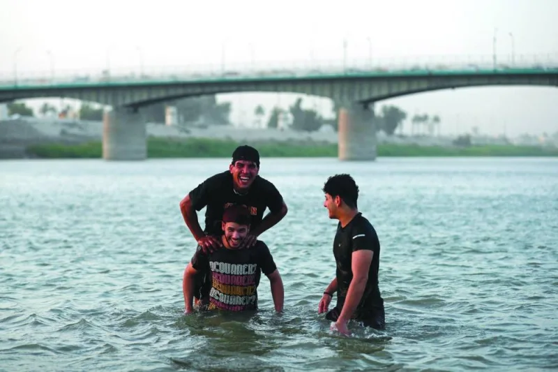 
An Iraqi dives into the waters of the Tigris river in Baghdad, as temperatures soared past 45C. Below: Iraqi youths play in the receding waters of the Tigris river. 