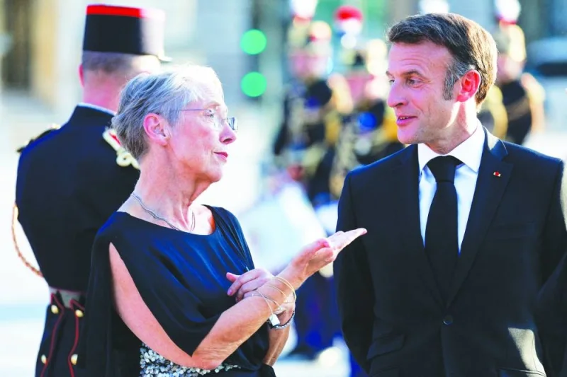 French President Emmanuel Macron (left) and Prime Minister Elisabeth Borne converse as they arrive to attend a dinner held at the Louvre in Paris on Friday. (Reuters)
