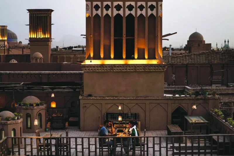 
This picture shows a view of wind catchers in Iran’s central city of Yazd. Right: A couple sit by a wind catcher at a rooftop cafe in Yazd. 