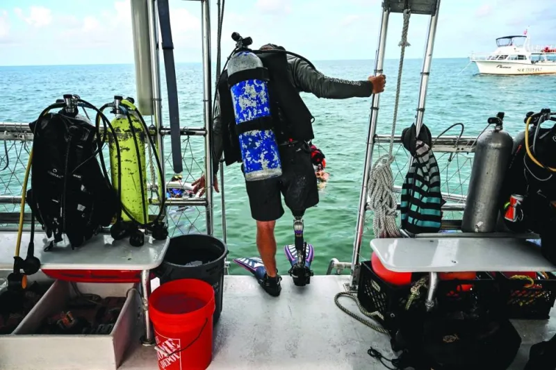 
A member of the CWVC, Billy Costello, who has a prosthetic leg, gets ready to descend into the water to plant corals in a reef. 